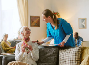 aide and senior woman smiling at each other