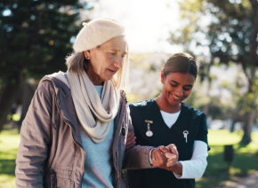 aide assisting the senior woman to walk