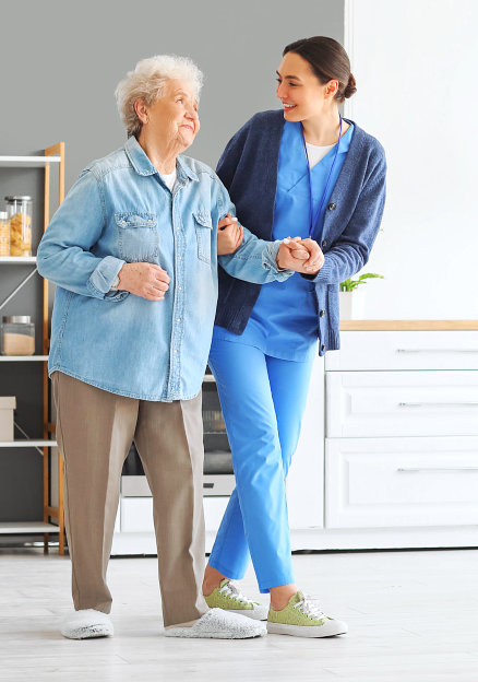 aide smiling while holding the senior woman hand