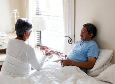 aide assisting the senior man on his medicines