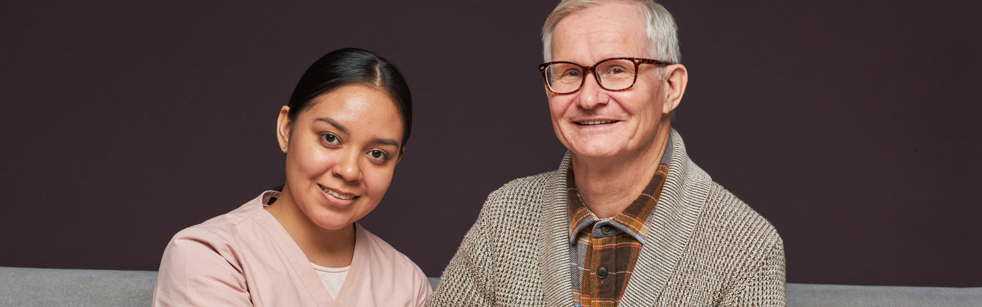 aide and senior man smiling